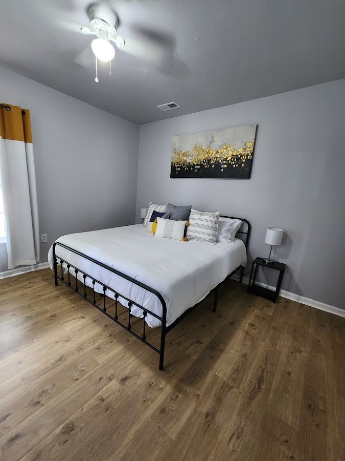 Tidy bedroom with metal bed frame and wood flooring