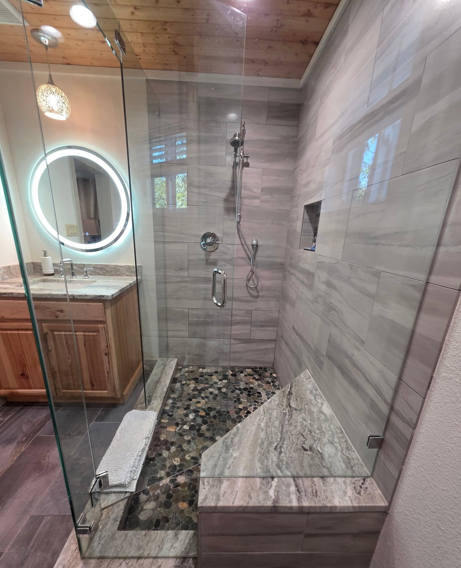 Spotless glass-enclosed shower with river-stone floor
